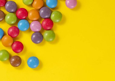 Rengarenk şeker esintilerinin renkli arkaplanı. Sarı parlak arka planda dağınık şekerler..