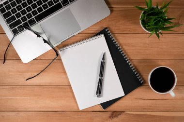 Sade kahve, dizüstü bilgisayar, defter ve gözlüklü eski ahşap masa..