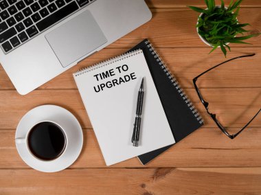 Sade kahve ve dizüstü bilgisayarlı ahşap masa, defter ve gözlük.