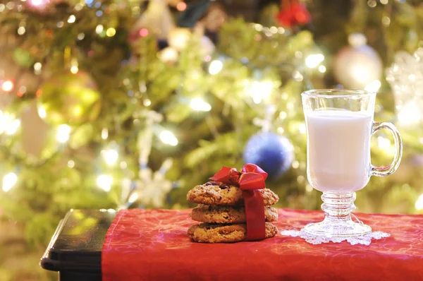 Copa de leche con galletas en la mesa bajo el árbol de Navidad —  Fotos de Stock