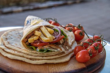 Yunan Gyros sokak yemekleri, domates, souvlaki, Yunan salatası, soğan ve patates kızartması ile güzelce paketlenmiş.  