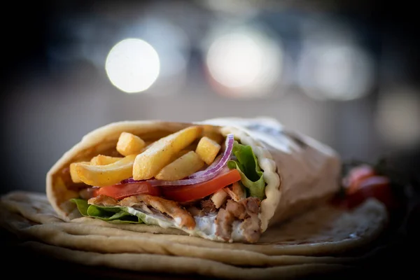 Yunan Gyros sokak yemekleri, domates, souvlaki, Yunan salatası, soğan ve patates kızartması ile güzelce paketlenmiş.  