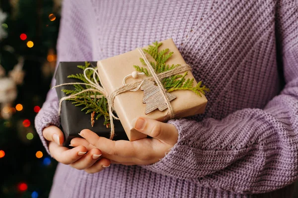 Menina segurando pequeno presente em suas mãos. árvore de Natal decorado no fundo. Cartão de Natal brilhante com espaço para texto — Fotografia de Stock