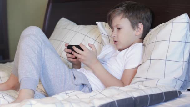 Unalmas gyerek játszik játék okos telefon — Stock videók