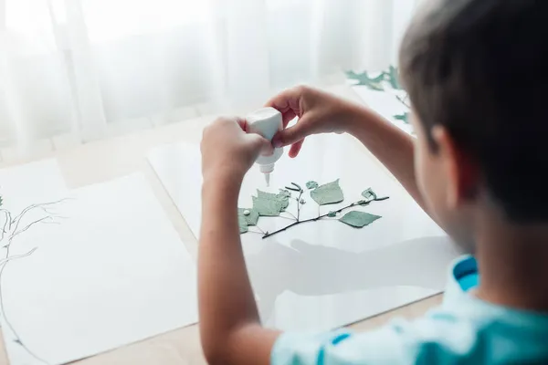 Klein kind zit aan het bureau en maakt foto 's van droge berkenbladeren — Stockfoto