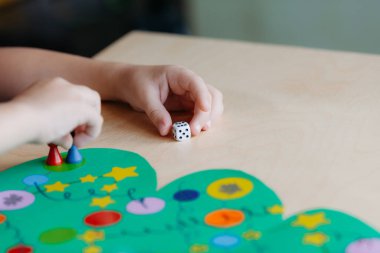 çocuk eli zarı atar ve çipi Noel oyun sahasında hareket ettirir