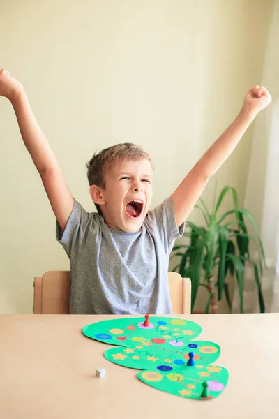 Ευτυχισμένο παιδί απολαμβάνει τη νίκη στο επιτραπέζιο παιχνίδι Χριστουγέννων Royalty Free Φωτογραφίες Αρχείου