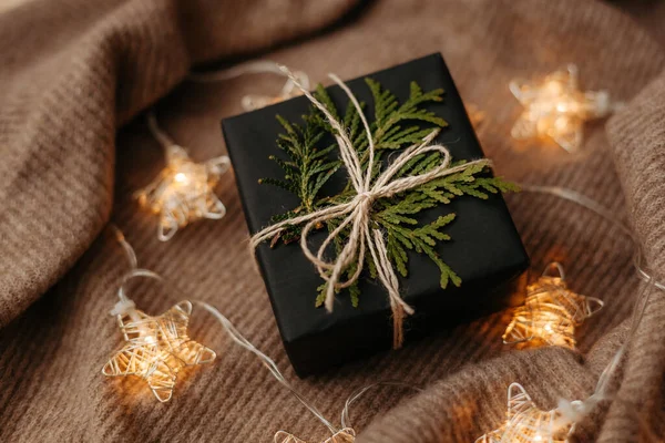 Christmas gift packed in black wrapping paper lying on soft woolen background — Stock Photo, Image