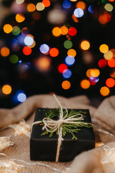Pequeno presente que põe no tecido bege, árvore de Natal decorada no fundo. — Fotografia de Stock