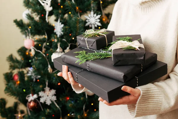Menina segurando pilha de caixas de presente em suas mãos. árvore de Natal decorado no fundo. — Fotografia de Stock