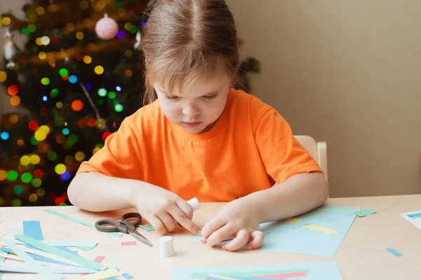 Kleines Mädchen bastelt Weihnachtskarte am Tisch — Stockfoto