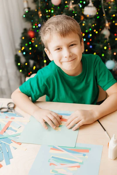 Kleiner Junge bastelt Weihnachtskarte am Tisch — Stockfoto