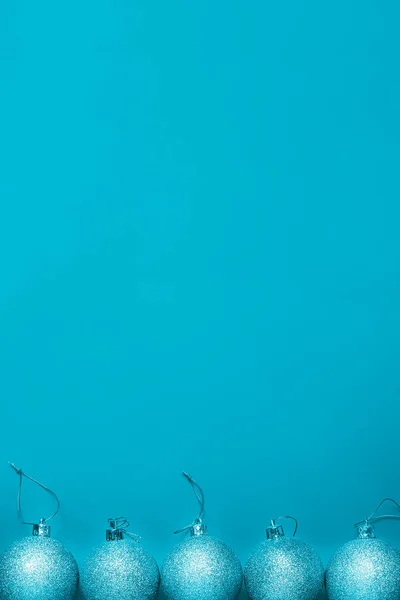 Beberapa bola Natal berbaring di baris pada latar belakang biru, format vertikal — Stok Foto