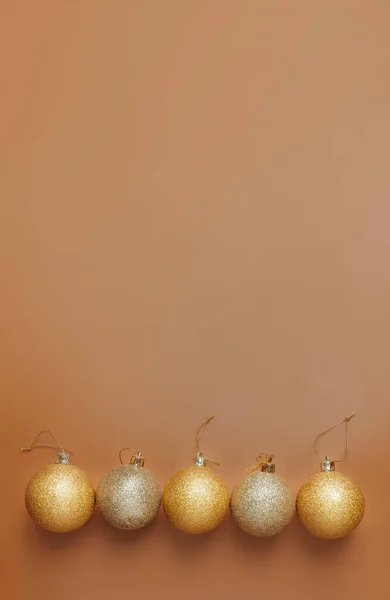 Vánoční míč ležící v řadě na oranžovém pozadí, vertikální formát — Stock fotografie