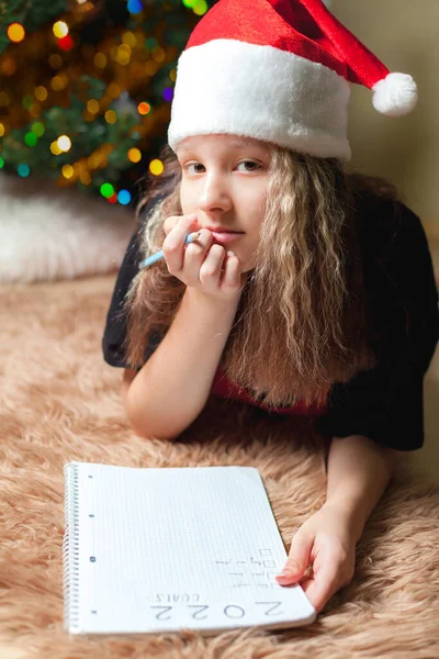 Tiener meisje liggen op de vloer in de buurt van kerstboom — Stockfoto