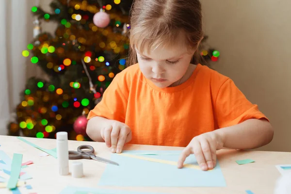 Маленька дівчинка робить різдвяну листівку, сидячи за столом — стокове фото