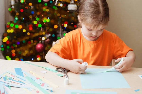 Kleines Mädchen bastelt Weihnachtskarte am Tisch — Stockfoto