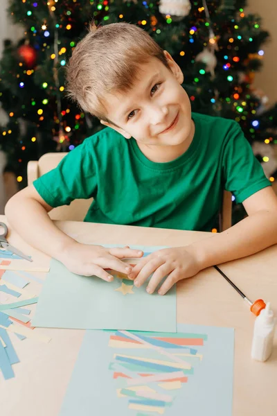 Little Boy podejmowania kartki świąteczne siedzi przy stole — Zdjęcie stockowe