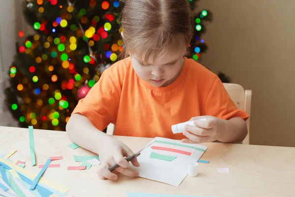 Meisje maken kerstkaart zittend aan tafel — Stockfoto