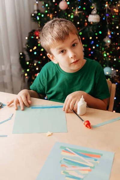 Little Boy podejmowania kartki świąteczne siedzi przy stole Zdjęcie Stockowe