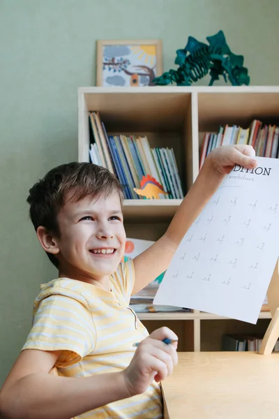 子供部屋の机に座って数学のレッスンをしている少年 — ストック写真