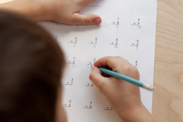 Seorang anak sekolah yang melakukan pelajaran matematika duduk di meja di ruang anak-anak — Stok Foto
