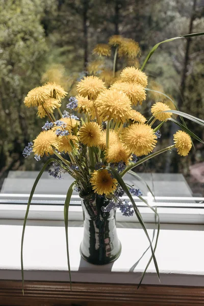 Bouquet of yellow dandelions in clay vase standing on windowsill by open window in countryside — Stock Photo, Image