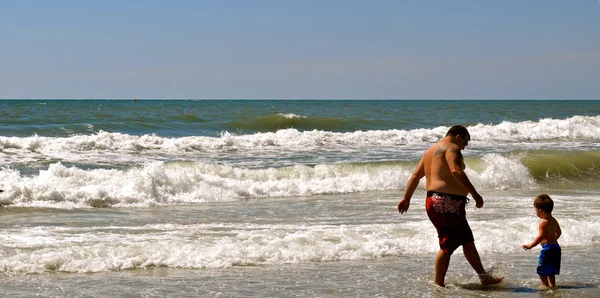 Батько і син плескають в океані-1 Ліцензійні Стокові Фото