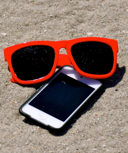 V písku - sluneční brýle ipod iphone 3 — Stock fotografie