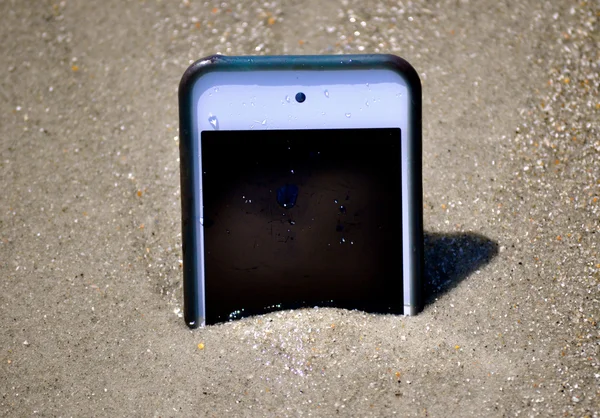 Smartphone i sand som liknar iPhone — Stockfoto