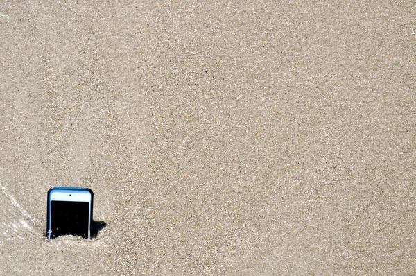 Smartphone i sand som liknar iPhone — Stockfoto