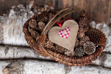 Sepetli, jüt kalpli ve çam kozalaklı Noel dekoru. Bir tebrik kartı veya hediye için mükemmel.