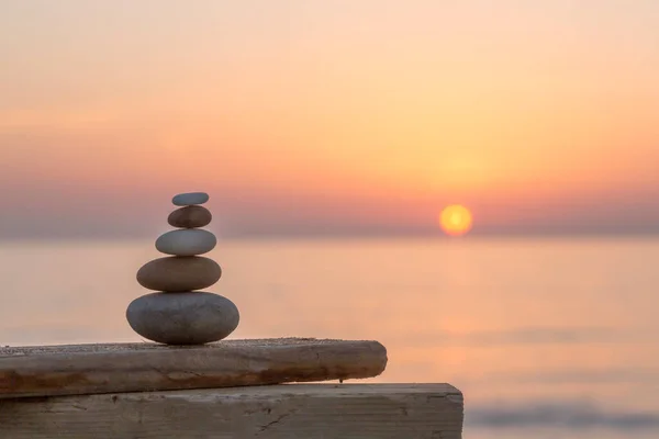 well balanced stone cairn from smooth pebbles at sunset on the spanish coast, perfect for a travel or lifestyle blog, postcard or gift bag