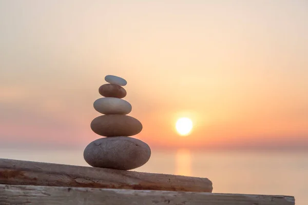 well balanced stone cairn from smooth pebbles at sunset on the spanish coast, perfect for a travel or lifestyle blog, postcard or gift bag