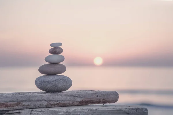 well balanced stone cairn from smooth pebbles at sunset on the spanish coast, perfect for a travel or lifestyle blog, postcard or gift bag