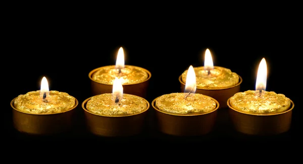 Velas douradas em um fundo preto . — Fotografia de Stock