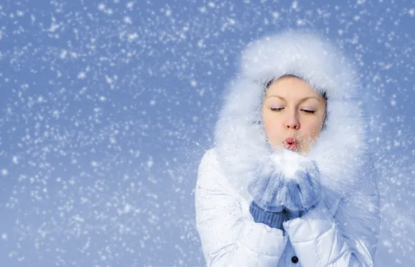 Flicka blåser bort snöflingorna från hand — Stockfoto