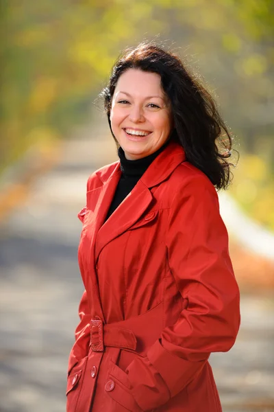 Riant une belle femme dans un manteau rouge — Photo