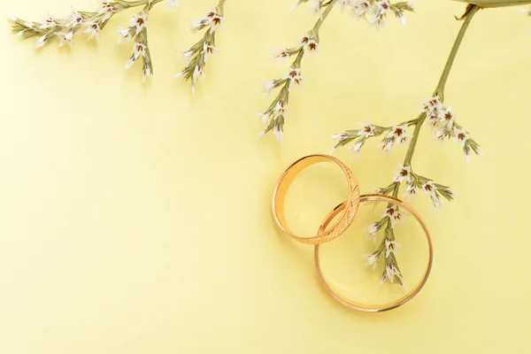 Gold wedding rings and branch flowers — Stock Photo, Image