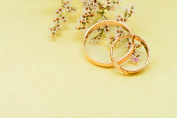 Χρυσά γαμήλια δαχτυλίδια και υποκατάστημα λουλούδια — Φωτογραφία Αρχείου
