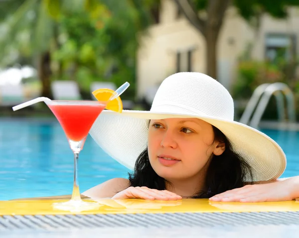 Girl with a cocktail at the edge of the swimming pool — Stock Photo, Image