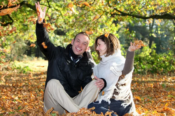 Pareja feliz jugando con hojas de otoño — Foto de Stock