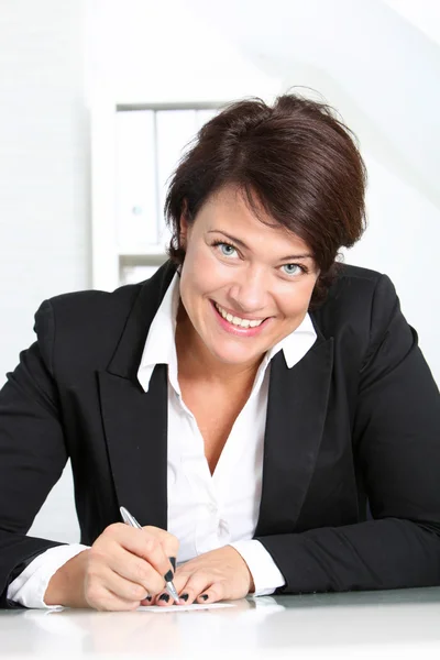 Mujer de negocios sonriente en su escritorio —  Fotos de Stock