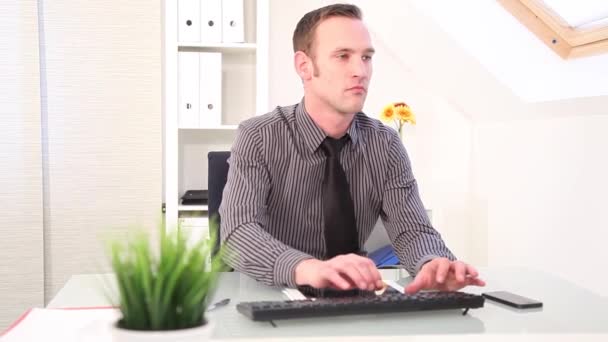 Empresario escribiendo en un teclado y hablando por teléfono — Stockvideo
