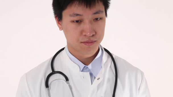 Primer plano de un joven médico asiático escribiendo en su portapapeles — Vídeo de stock