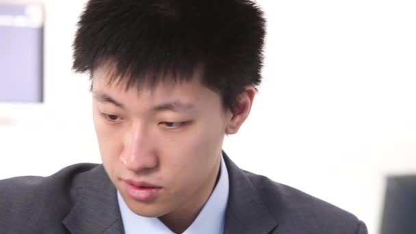 Young asian businessman writes on computer, closeup of head — Stock Video