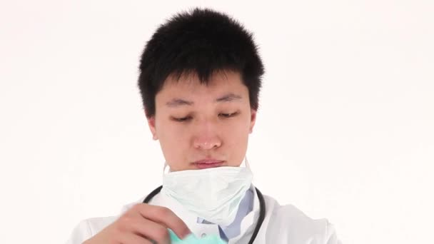 Besorgter asiatischer junger Arzt zieht Schutzkleidung an — Stockvideo