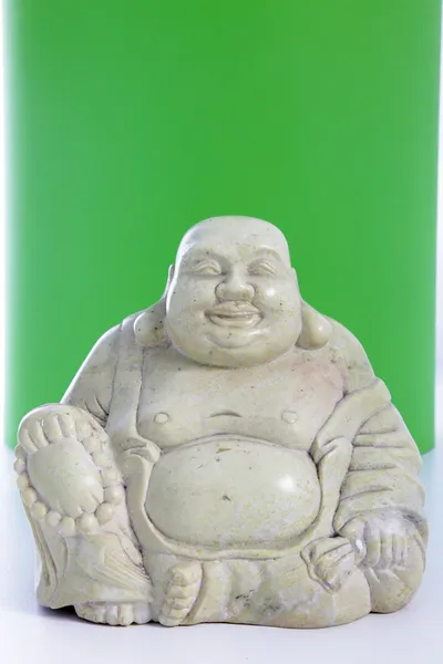Een beeldje van de buddha tegen een groene achtergrond — Stockfoto