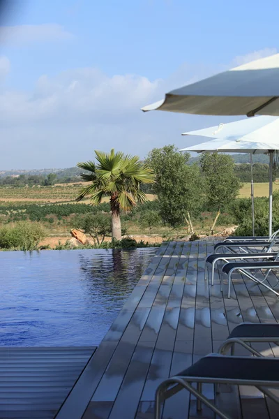 Reclinadores y sombrillas junto a la piscina — Foto de Stock