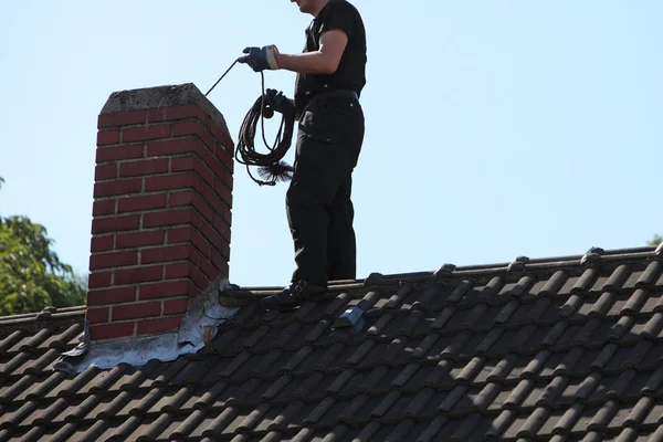 Schornsteinfeger putzt einen Schornstein — Stockfoto